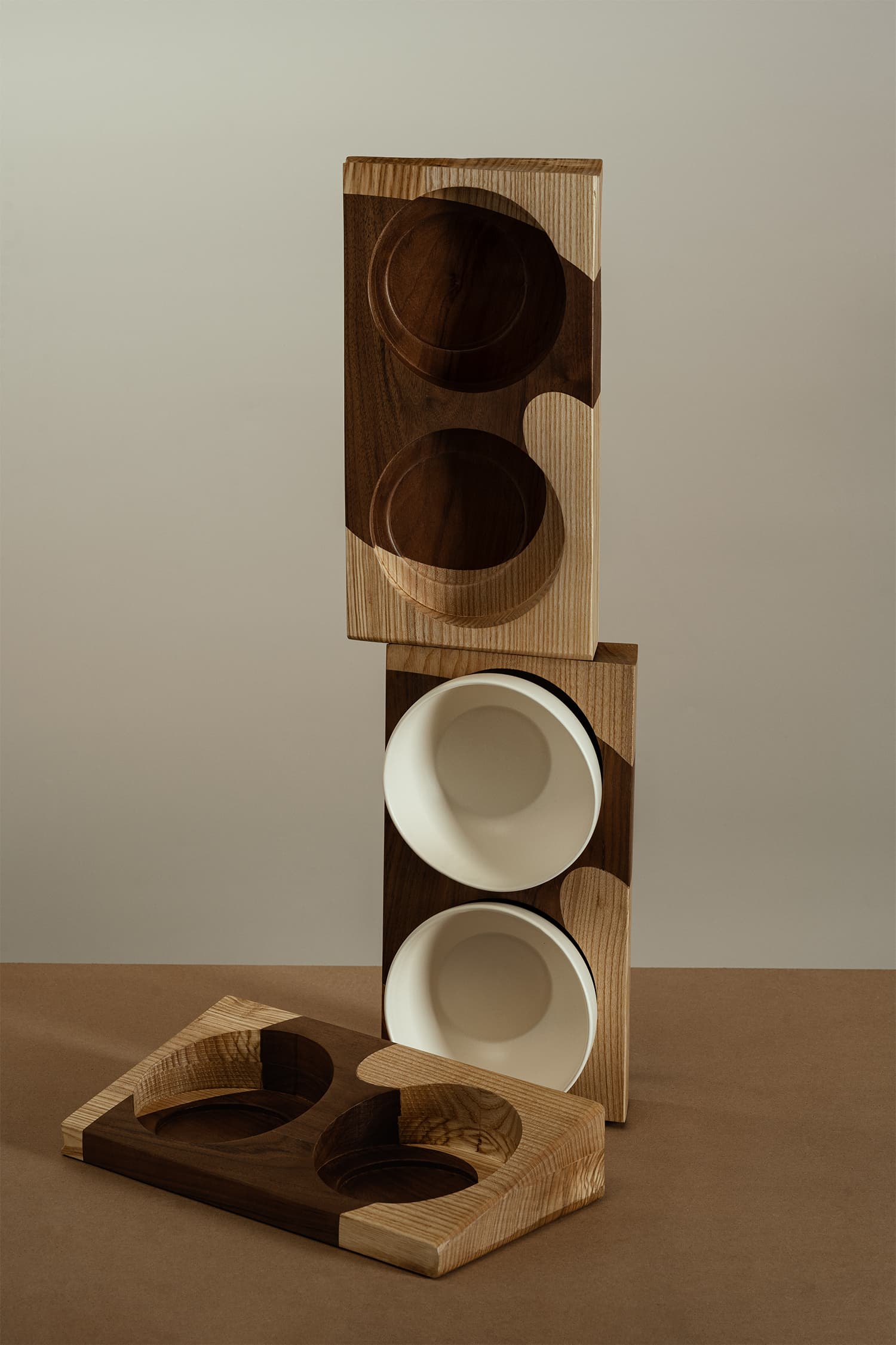 Three two-color wooden bases, with two white bowls placed on the middle base